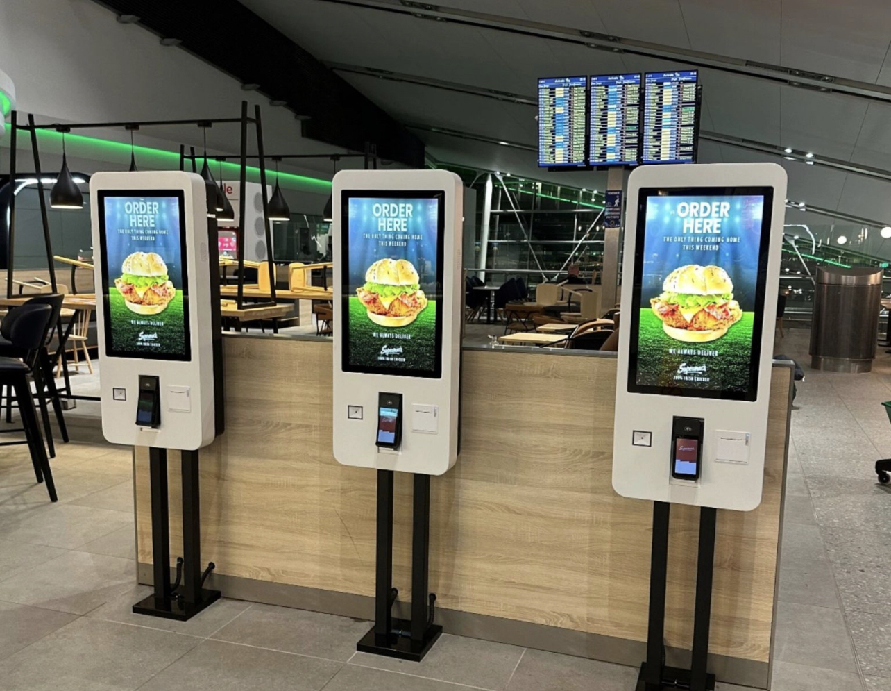 Trois bornes de commande alignées dans un food court